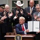 Surrounded by members of law enforcement, U.S. President Donald Trump holds up an executive order he signed on “Safe Policing for Safe Communities” during an event in the Rose Garden at the White House June 16, 2020 in Washington, DC.